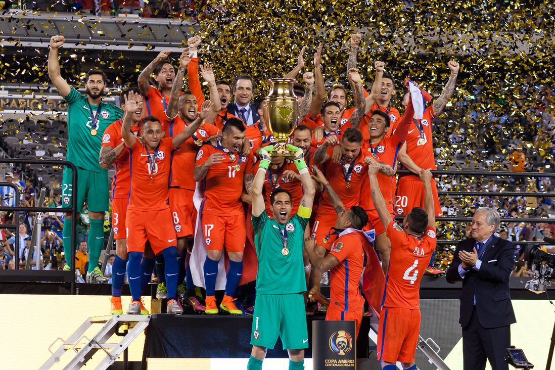 Chile captain Claudio Bravo lifts the Copa America Centenario trophy as teammates celebrate.